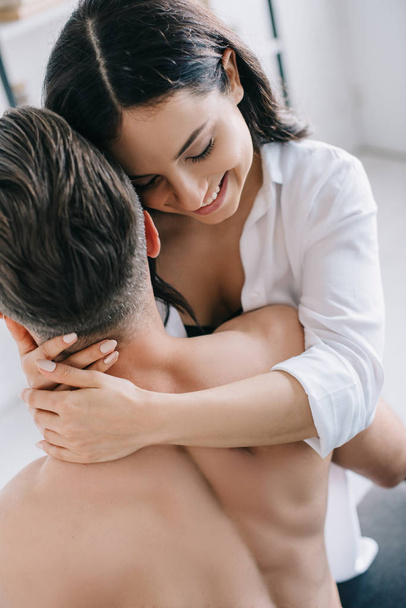 smiling and brunette woman in shirt hugging with shirtless man  - Foto, immagini
