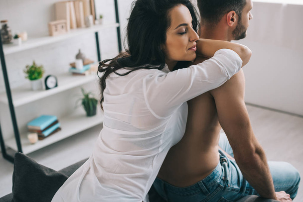 attractive and brunette woman with closed eyes in shirt hugging with man  - Fotoğraf, Görsel