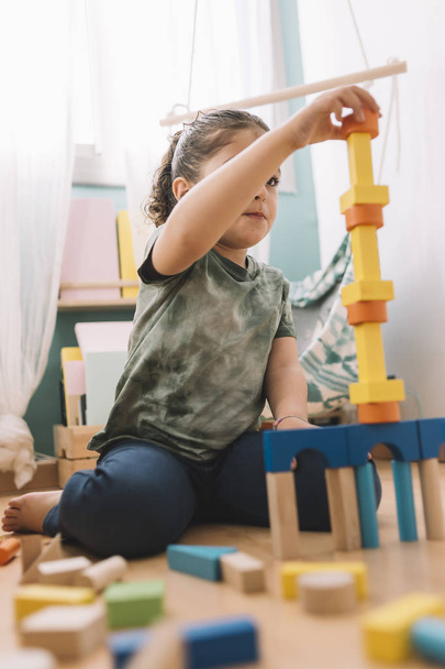 little girl plays with colorful building blocks - Fotó, kép