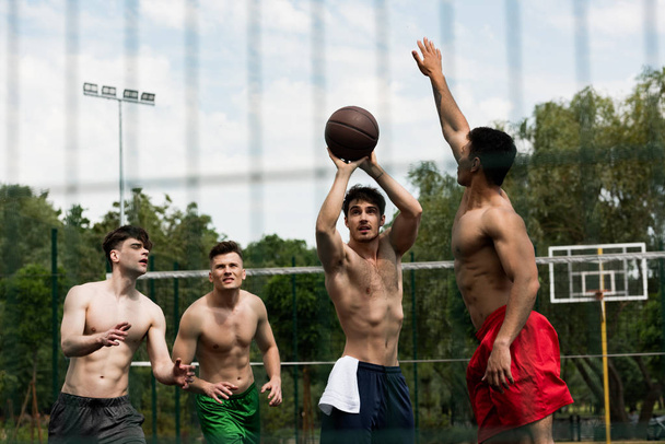 избирательное внимание спортсменов без рубашек, играющих в баскетбол на баскетбольной площадке
 - Фото, изображение