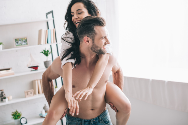 handsome man in jeans and smiling woman in shirt playing  - Fotoğraf, Görsel