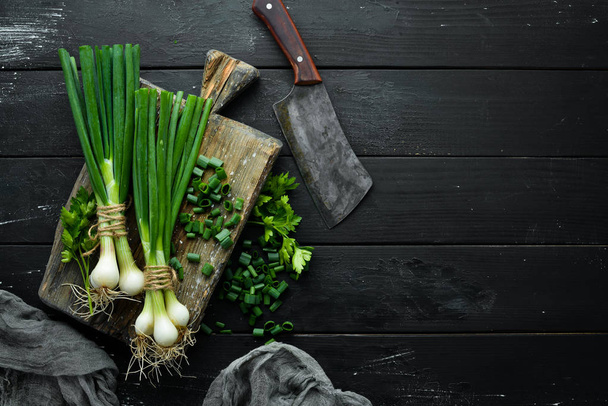 Green onion on a wooden table. Fresh vegetables. Top view. Free space for text. - Zdjęcie, obraz