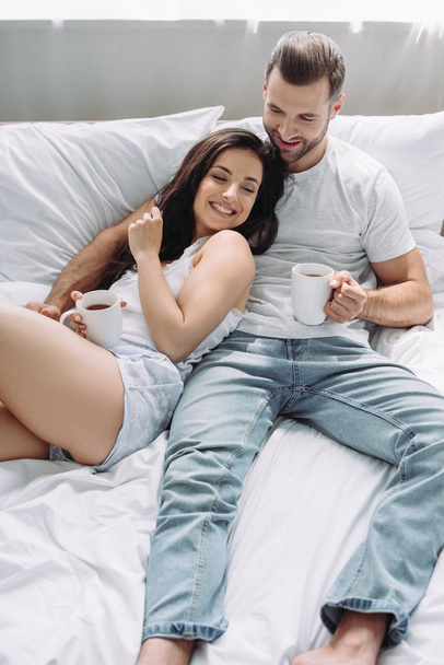 attraente e bruna donna e uomo sdraiato sul letto e abbracciare
  - Foto, immagini