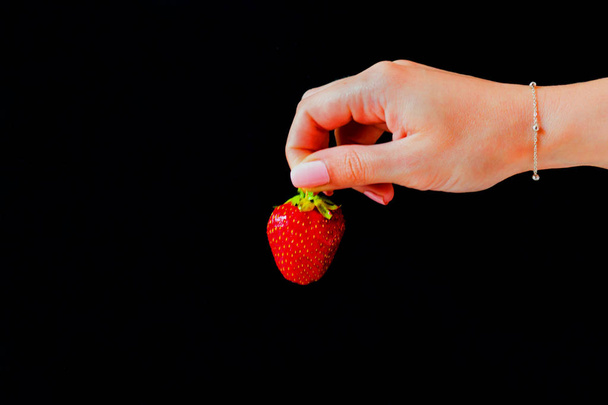 Fresas sobre un fondo negro en la mano de una niña.Copiar espacio
. - Foto, Imagen