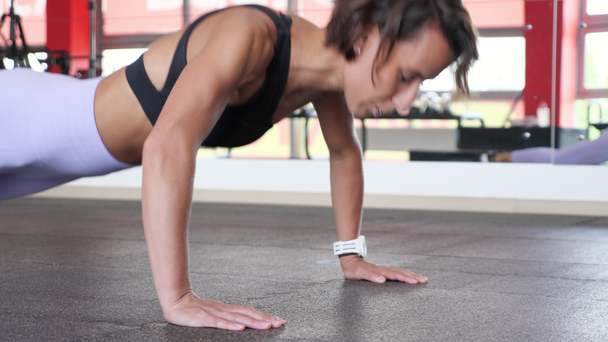 Athletic érett nő csinál meg a ripsz push-up-tól a padlót edzőteremben. - Felvétel, videó