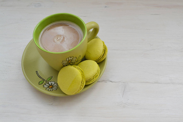 Пирожное макарон или макарон и чашка кофе на потрепанном столе с копировальным местом
 - Фото, изображение