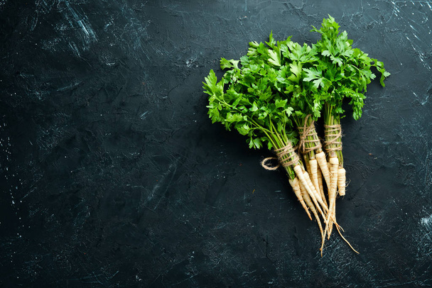Root parsley and parsley on a black background. Top view. Free space for your text. - Photo, Image