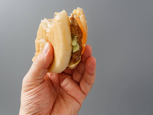 gebissene große Burger mit Schnitzel und Tomate auf grauem Hintergrund - Foto, Bild