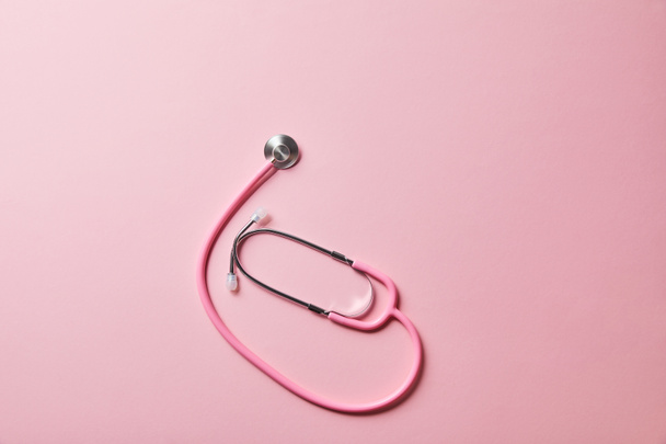 top view of pink stethoscope on light pink background - Foto, imagen