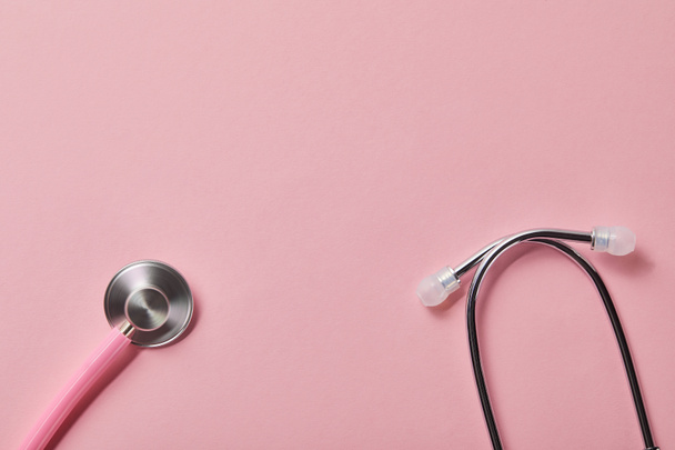 top view of pink metal stethoscope on light pink background - Φωτογραφία, εικόνα