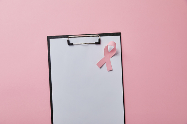 breast cancer ribbon on folder with empty paper isolated on pink  - Photo, Image