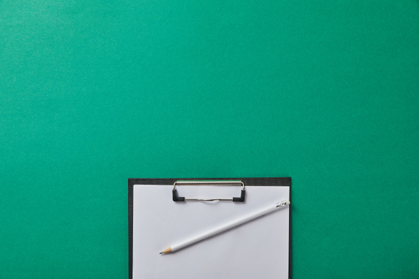 vista superior del lápiz en la carpeta con papel en blanco aislado en verde
 - Foto, Imagen