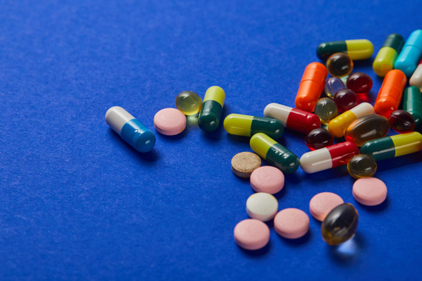 eri värikäs hajallaan lääketieteen pillereitä sinisellä taustalla
 - Valokuva, kuva