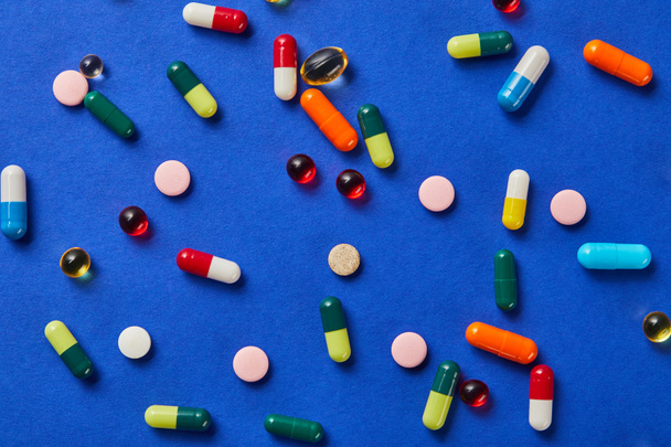 Top zicht van verschillende medische pillen op blauwe achtergrond - Foto, afbeelding