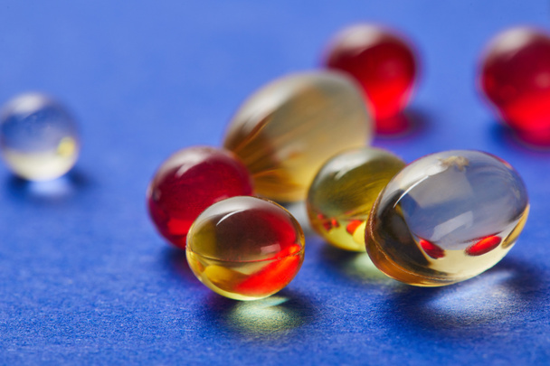 Close-up van visolie en E-vitaminen op blauwe achtergrond - Foto, afbeelding