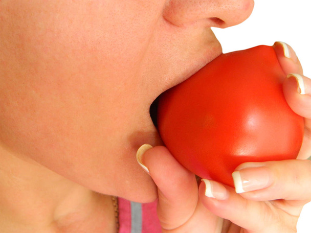 Vrouw bijt en eet tomaat close-up afbeelding. Gezichtsdeel met mou - Foto, afbeelding