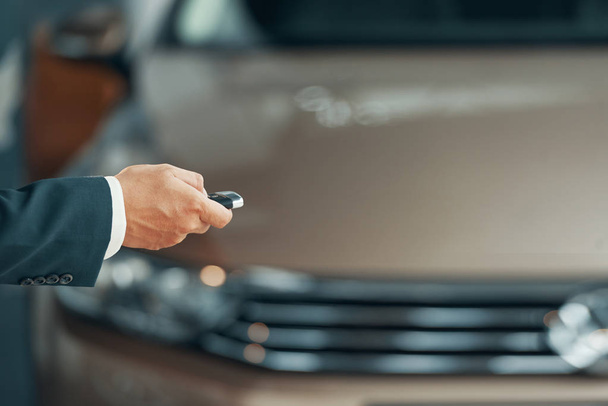 Omistajan käsi, joka käyttää sähköistä auton avainta oven avaamiseen
 - Valokuva, kuva
