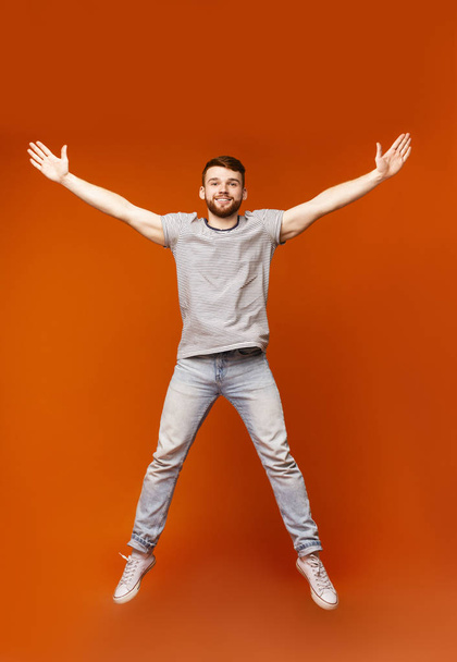 Junger Millennial-Mann springt mit offenen Händen - Foto, Bild