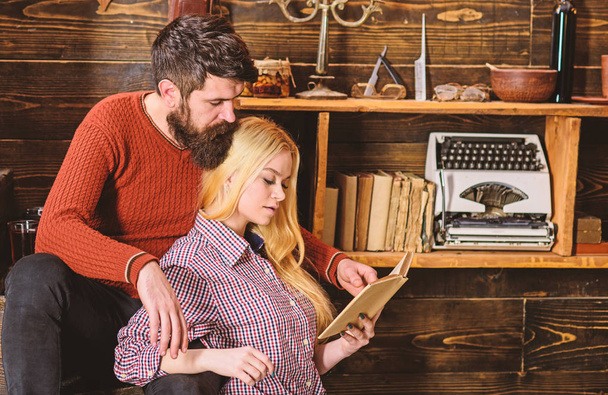 Couple in wooden vintage interior enjoy poetry. Romantic evening concept. Lady and man with beard on dreamy faces with book, reading romantic poetry. Couple in love reading poetry in warm atmosphere - Foto, Bild