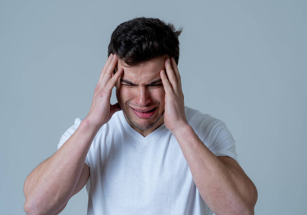 Close up of young sad latin man with strong headache and migraines looking worried in emotional pain. Feeling sorrow and depression. Isolated in neutral background in People and Health care concept. - Photo, Image