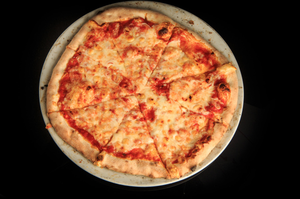 top view of whole sliced cheese pizza on round white plate - Photo, Image