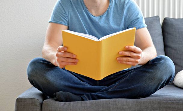 мужчина читает книгу на диване
 - Фото, изображение