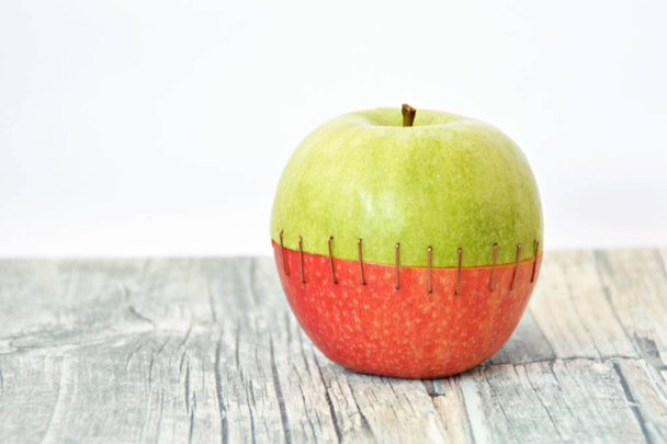 Combine la parte superior de una manzana verde con el trasero de una roja cosiéndolas juntas
 - Foto, imagen