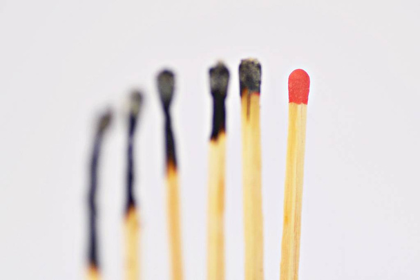 On a white, bright surface are many burned matches, only a single is intact and has a red head - concept for a competition from which only one person can emerge victorious - Photo, Image
