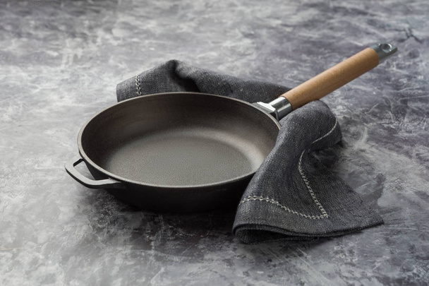 Empty cast iron frying pan on dark grey culinary background. - Foto, immagini