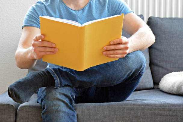 мужчина читает книгу на диване
 - Фото, изображение