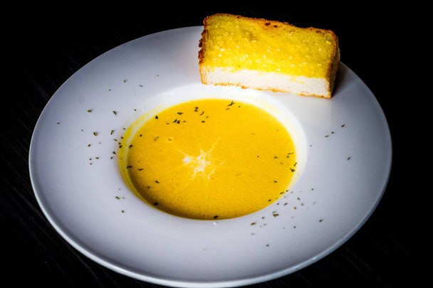 Crème maison de soupe à la citrouille servie avec un filet de crème et de pain à l'ail
  - Photo, image