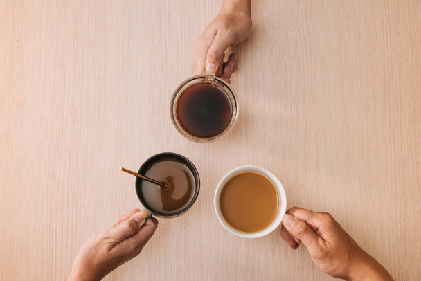 Hands holding cups of coffee on wood background - Photo, Image