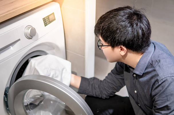 Asiatique homme cueillette vêtements de machine à laver
 - Photo, image