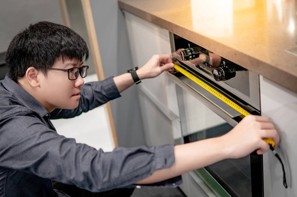 Asiatique homme à l'aide de ruban à mesurer sur four
 - Photo, image