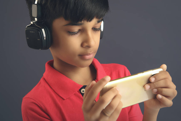 Indian young boy listen music with headphone and holding mobilephone - Foto, imagen