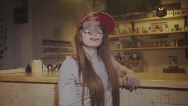 Une jeune jolie femme en bonnet rouge fume une cigarette électronique à la boutique de singes. Gros plan. Mouvement lent
. - Séquence, vidéo