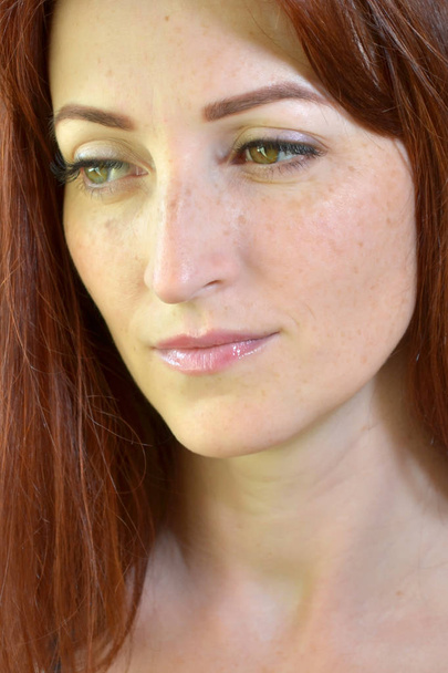 Белая девушка с рыжими волосами и зелеными глазами с наращиванием ресниц на темном фоне, смотрящим вниз
 - Фото, изображение