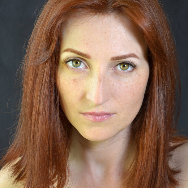 Fehér lány vörös haj és zöld szemek szempilla kiterjesztések sötét háttér néz ki egyenes - Fotó, kép