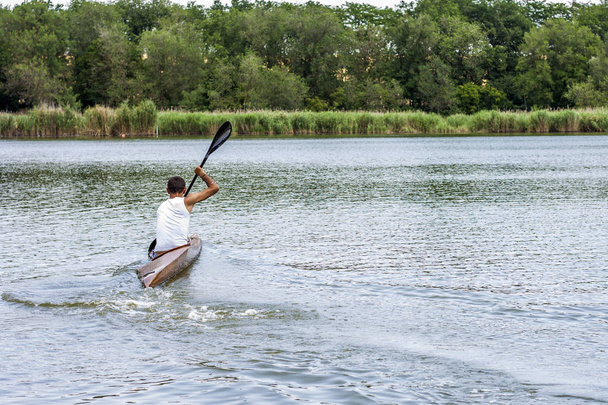 Rear view of a kayaker man paddle a canoe on a canal. - Fotoğraf, Görsel