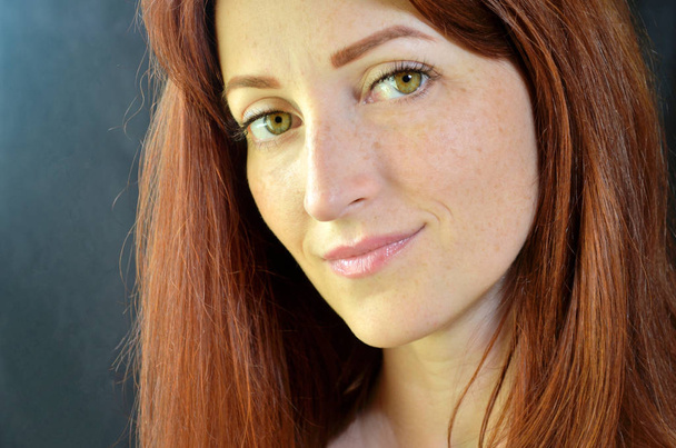 Menina branca com cabelos vermelhos e olhos verdes com extensões de pestanas no fundo escuro olhando para a frente com brilho
 - Foto, Imagem