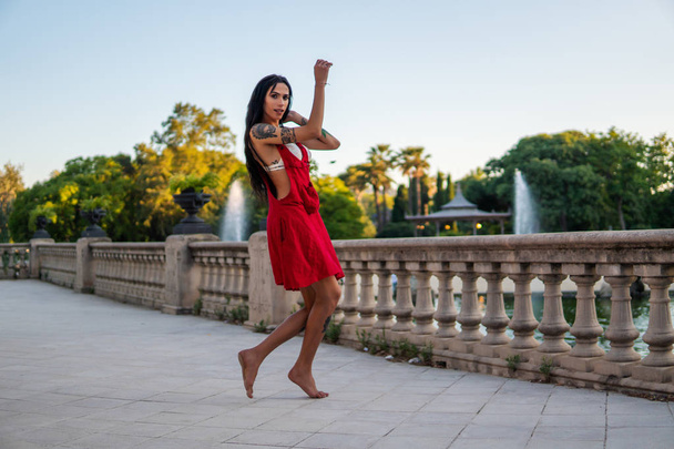 Ladyboy tattooed transgender model is dancing in the green park - Photo, Image