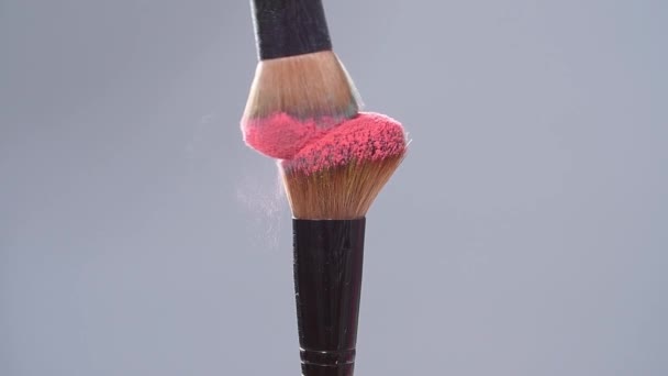 Make-up brush with pink powder splashes explosion on gray background on slow motion - Кадры, видео