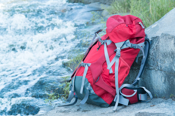 tourist backpack stands near a mountain river - 写真・画像