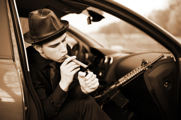 Mann im Auto mit Zigarre und Gewehr - Foto, Bild