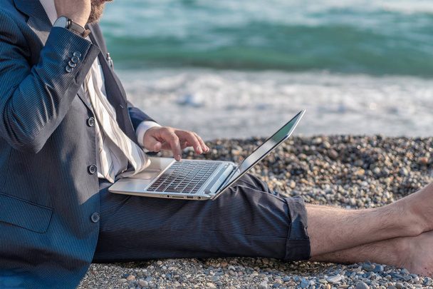 Homem de negócios sênior trabalhando em seu laptop deitado na praia
 - Foto, Imagem