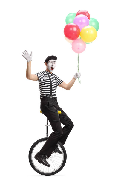 Mime on a unicycle holding a bunch of colorful balloons and wavi - Zdjęcie, obraz