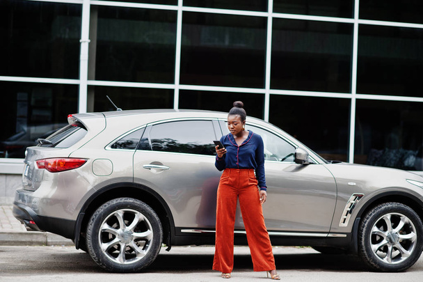 Rich business african woman in orange pants and blue shirt posed - Photo, Image
