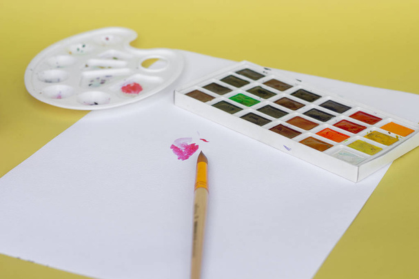 Renkli kuru suluboya tablet seti ve beyaz plastik palet ve beyaz doku arka plan, sanat ve eğitim nesnesi üzerinde boya fırçaları ve kalemler. Ön görünüm - Fotoğraf, Görsel