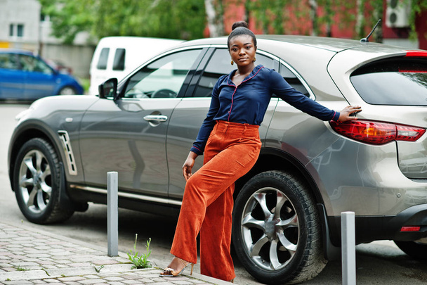 Πλούσια επιχειρηματική αφρικανική γυναίκα με πορτοκαλί παντελόνι και μπλε πουκάμισο που ποζάρει - Φωτογραφία, εικόνα