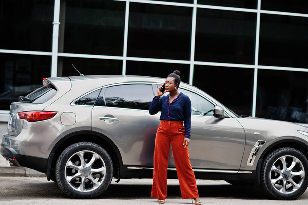 Rich business african woman in orange pants and blue shirt posed - Fotó, kép